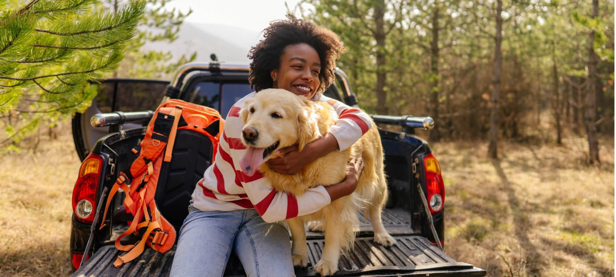 woman and her retriever dog sitting on the back of a pickup truck