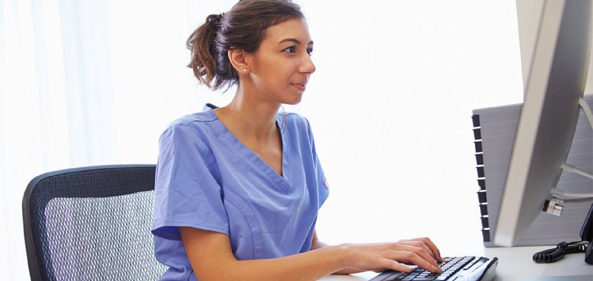 vet tech smiling while looking at her computer online