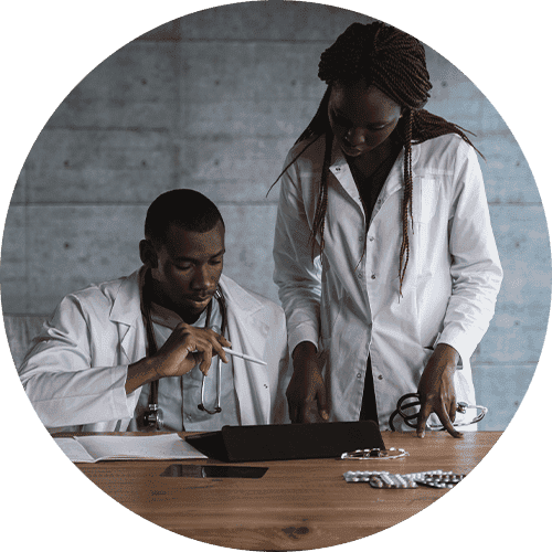 Two veterinary doctors intently gazing at a tablet screen on a desk.