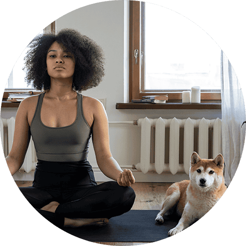 a woman meditating with her dog beside her
