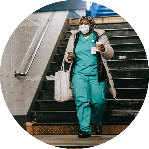 Image of a veterinary worker walking down the subway stairs with a coffee in their hand.