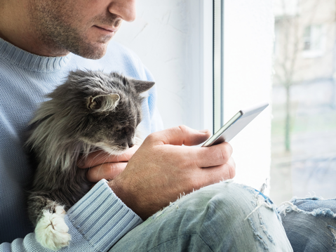 man with cat looking at mobile phone
