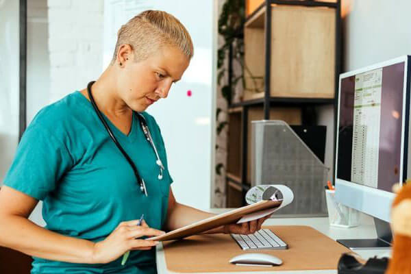 vet in front of computer, looking at clipboard