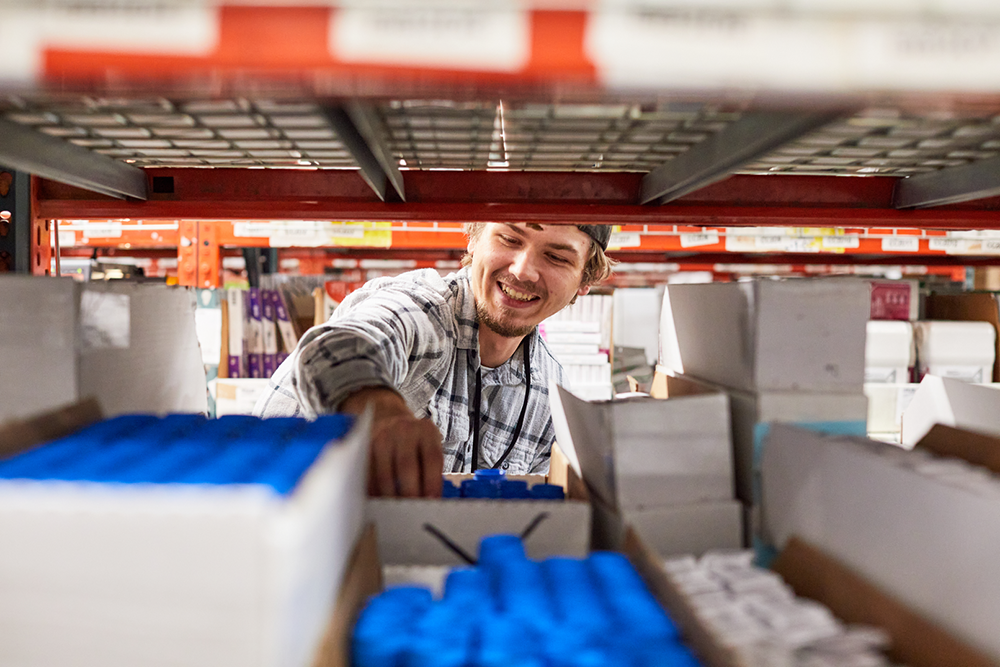 View of pharmacy technician smiling as he fulfills orders